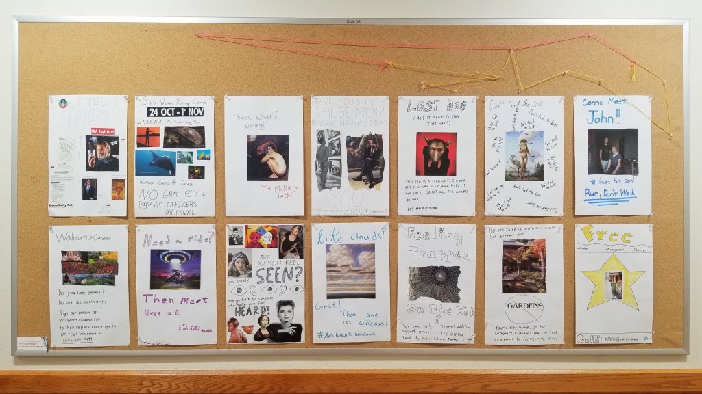 Bulletin board with multiple student posters pinned up. 
