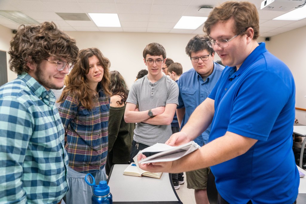 A student shows off his commonplace book to classmates.