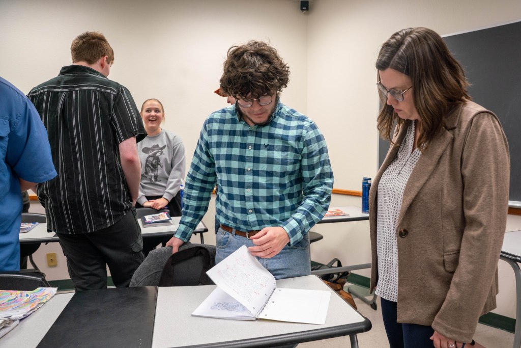Dr. Erica Haugtvedt watches a student show off his commonplace book.